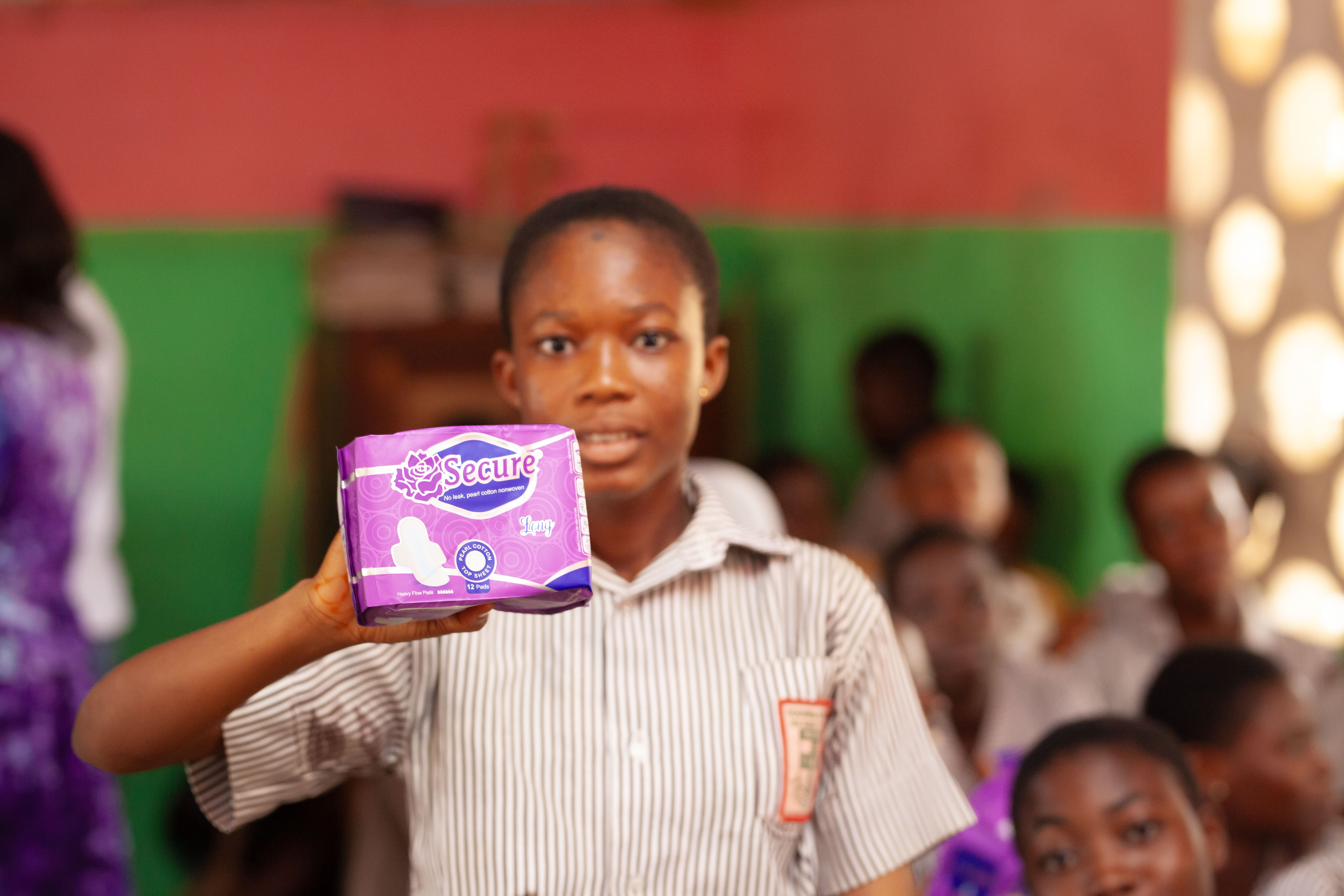 A student displays menstrual hygiene supplies received during the outreach.